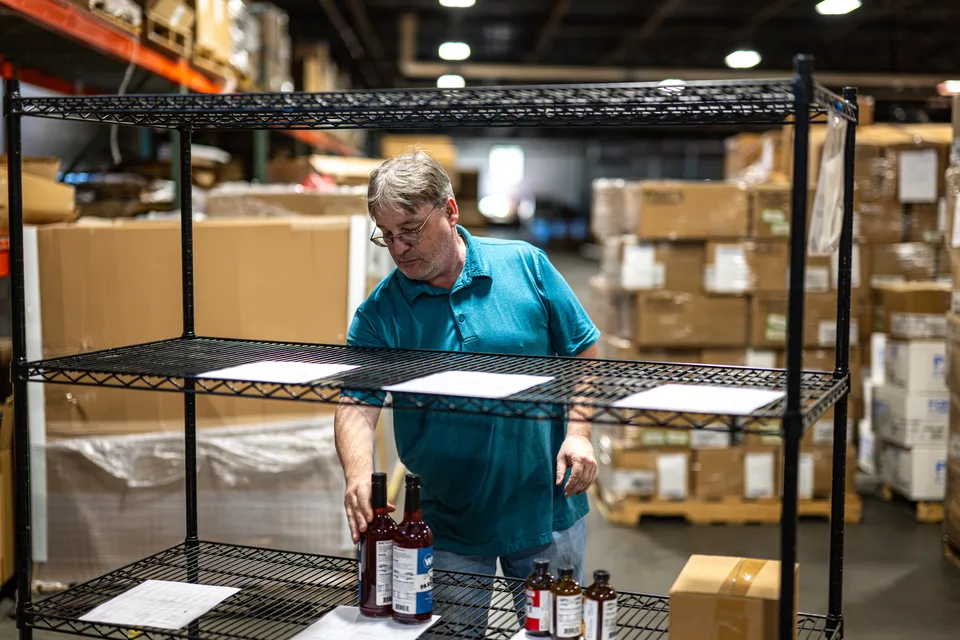 Order picker placing bottled product on staging shelves