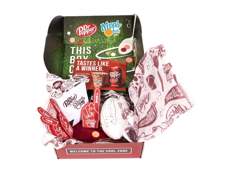 Game-day promotional kit — open box with foam fingers, can cooler, football, and insert card